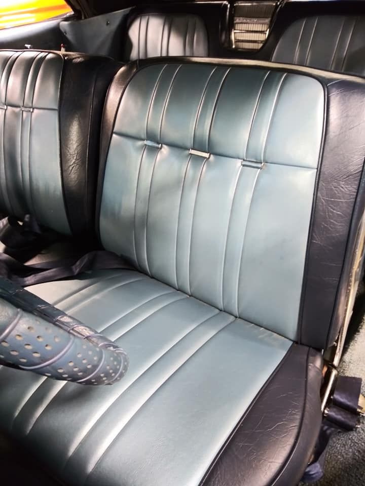 Vintage car interior featuring two-toned light blue and dark blue vinyl bench seats.