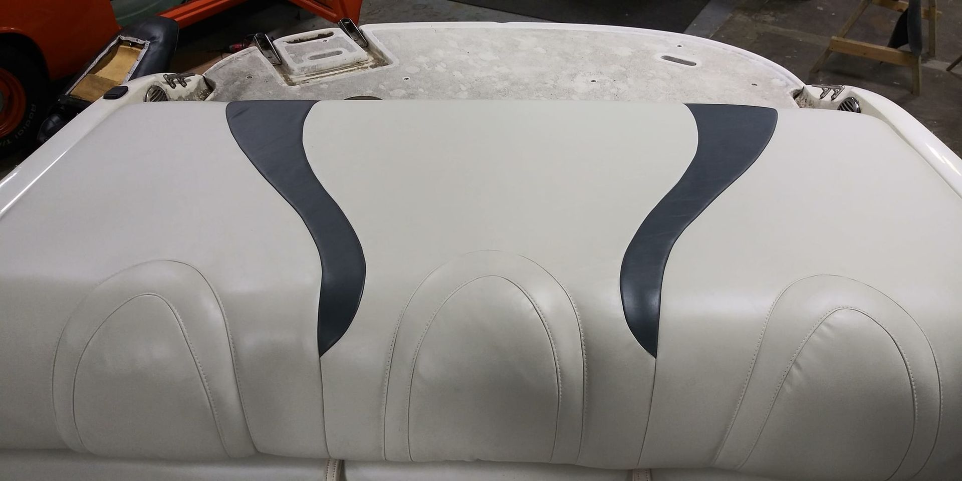 A light gray and dark gray upholstered boat bench seat viewed from above in a workshop.