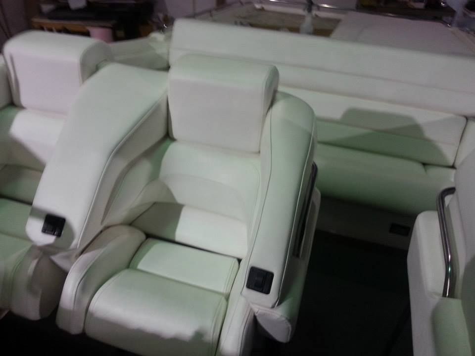 White marine-grade boat seating with integrated armrests and cushions arranged in a cockpit or cabin.
