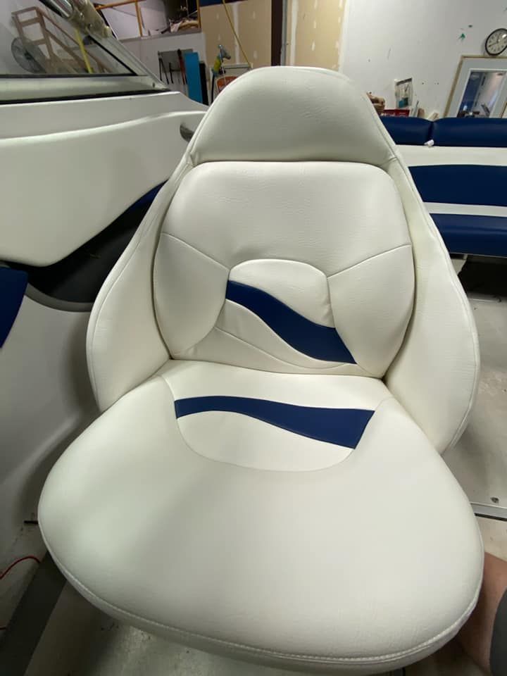 A white boat captain's chair featuring blue accent stripes on the seat and backrest, positioned inside a boat.