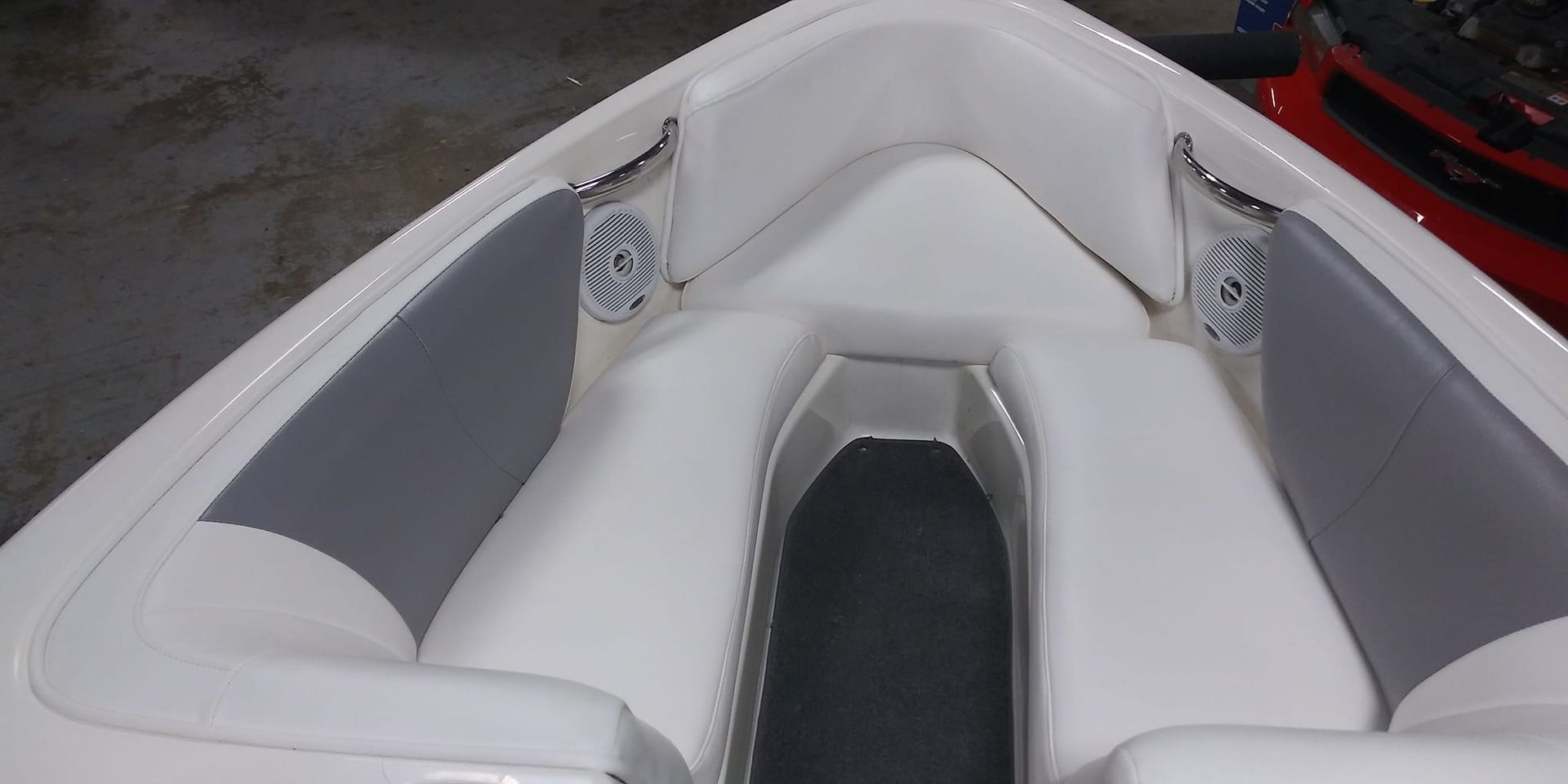 U-shaped bow seating area on a boat with white and gray vinyl cushions and built-in speakers on both sides.