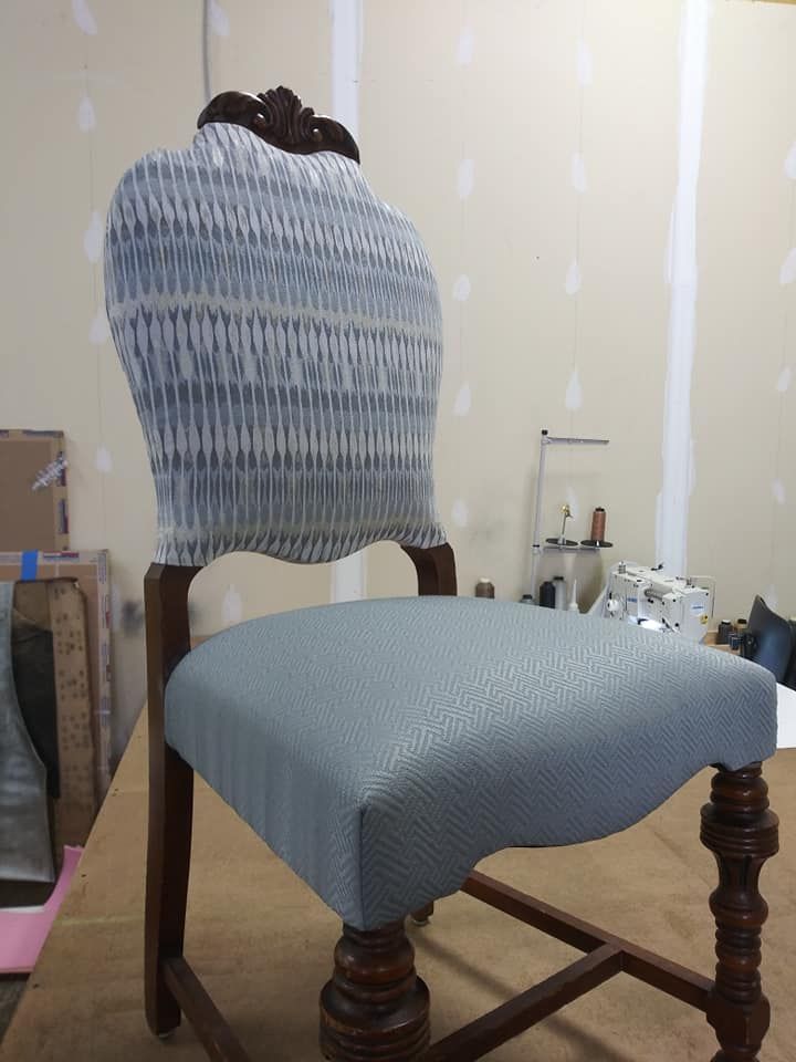 A refurbished wooden dining chair featuring a light blue textured seat and a patterned blue-and-white ikat backrest.