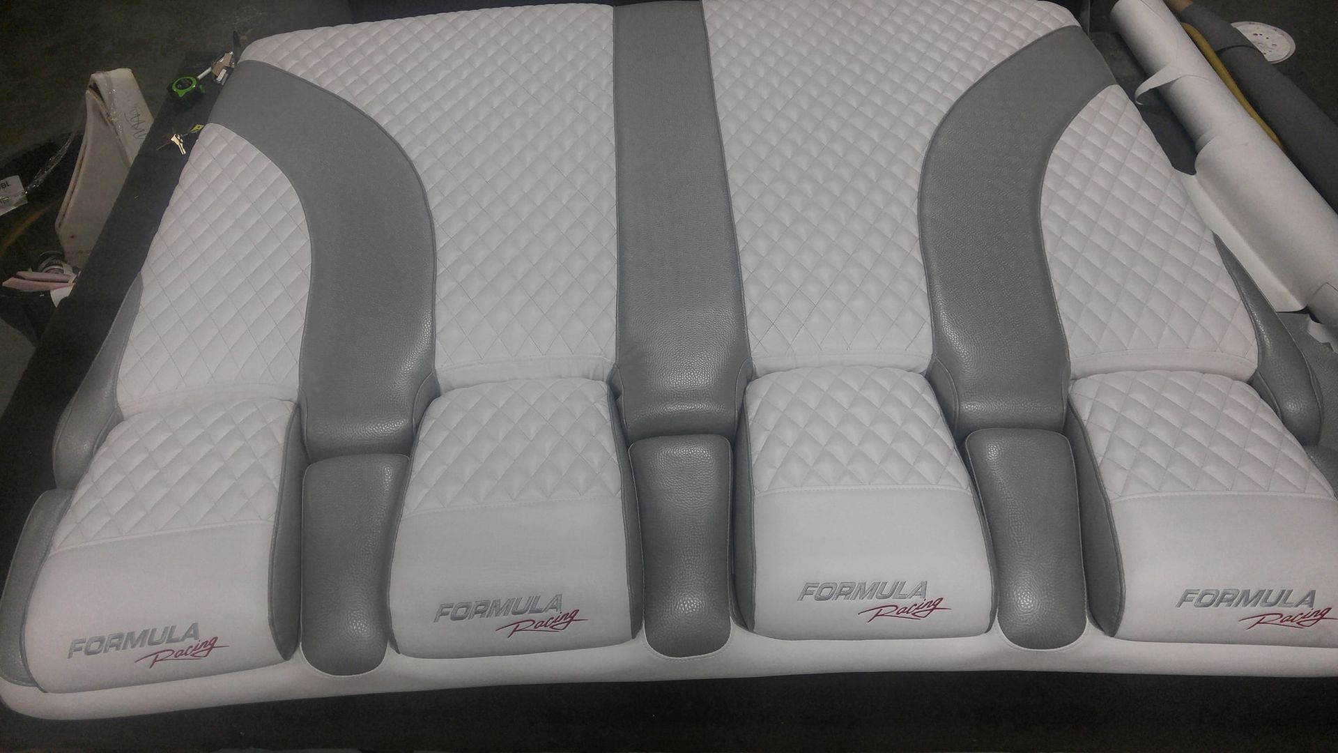 A white and gray boat bench seat with diamond-stitched padding and embroidered Formula boat logos on the bottom cushions.