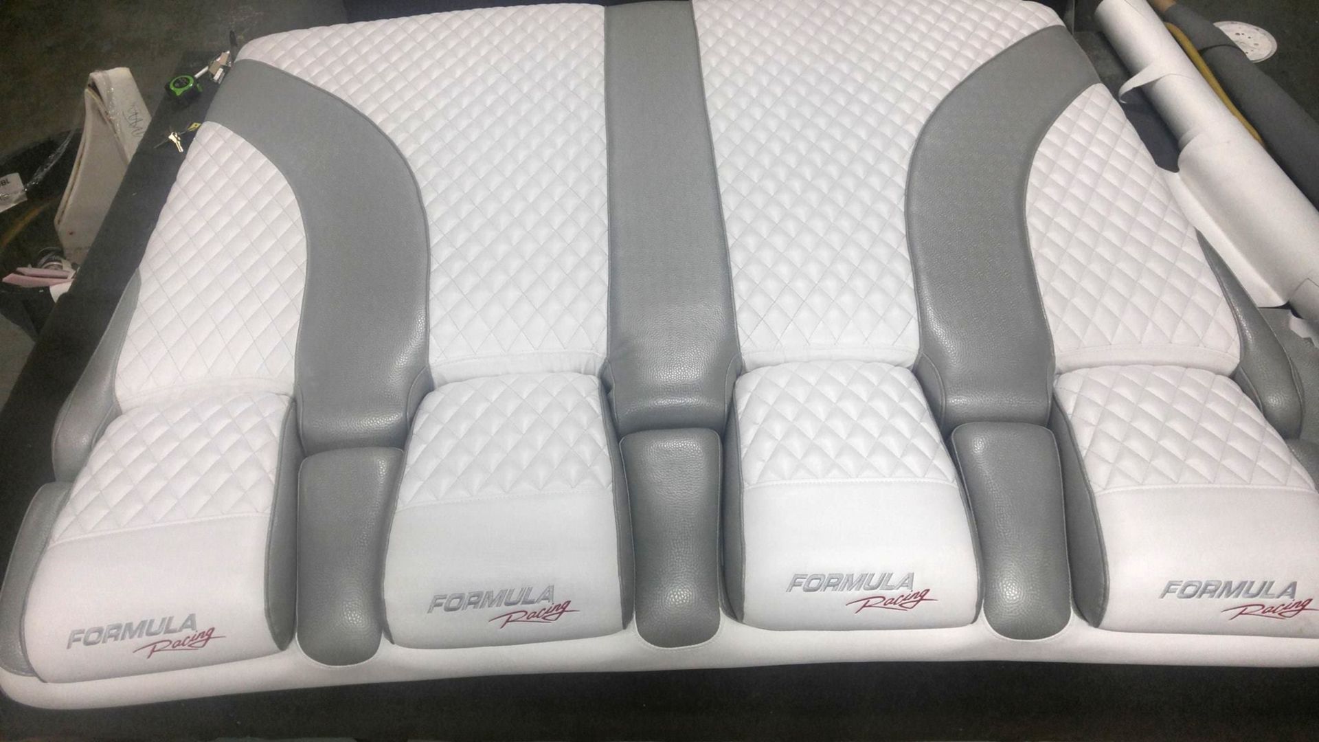 A boat seat cushion with white diamond-stitched panels, gray accents, and the 