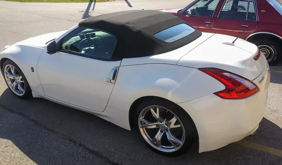 A white Nissan 370Z convertible parked outdoors, seen from the rear three-quarter angle.
