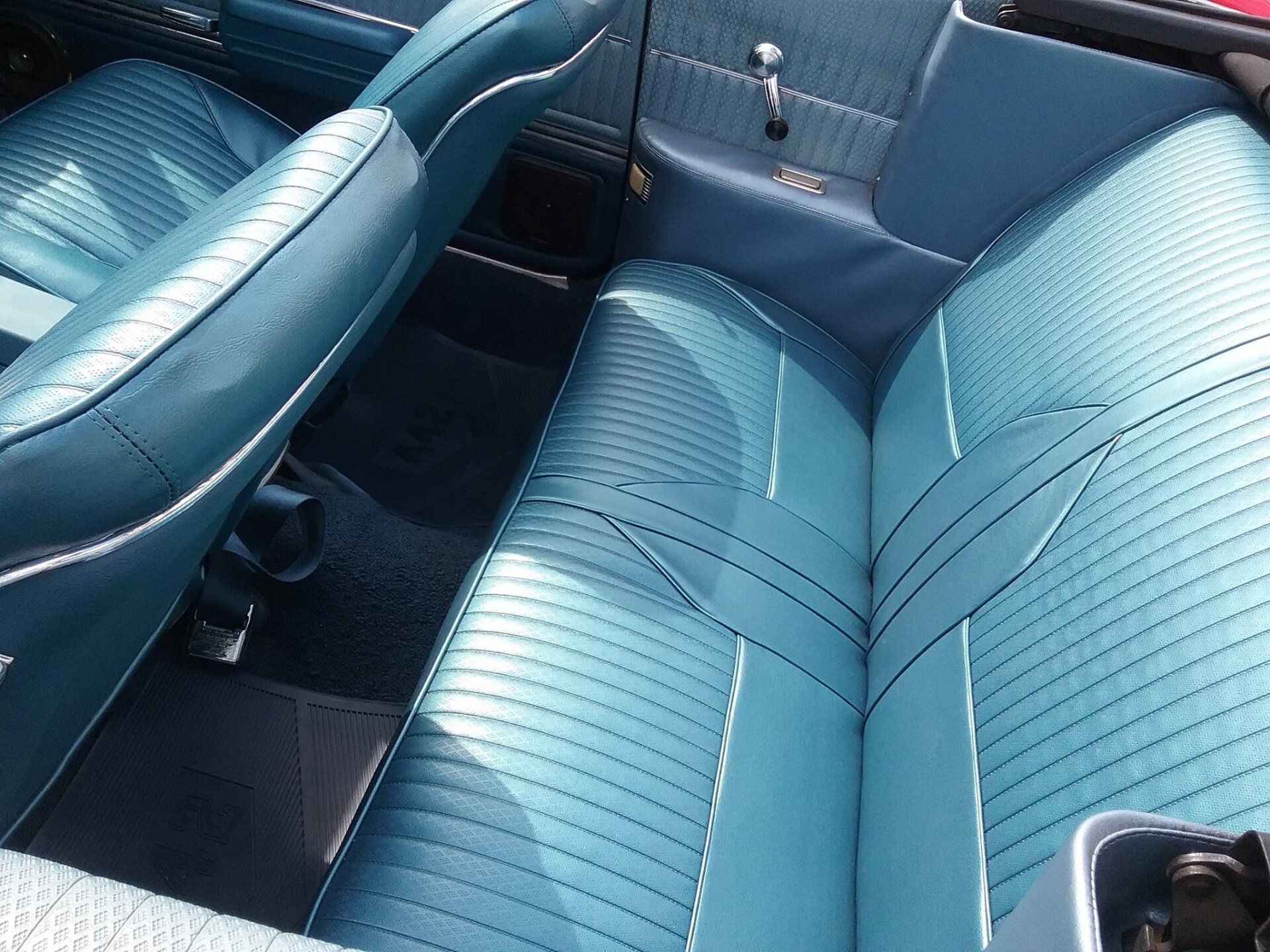 Blue vinyl bench seating in the interior of a vintage convertible car.