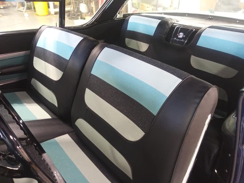 Interior of a vintage car with black, light blue, and white striped bench seats and matching door panel trim.