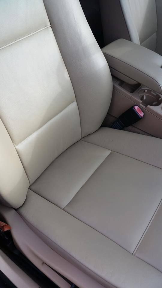 A close-up, high-angle shot of a beige leather car seat and center console with a seatbelt buckle visible.