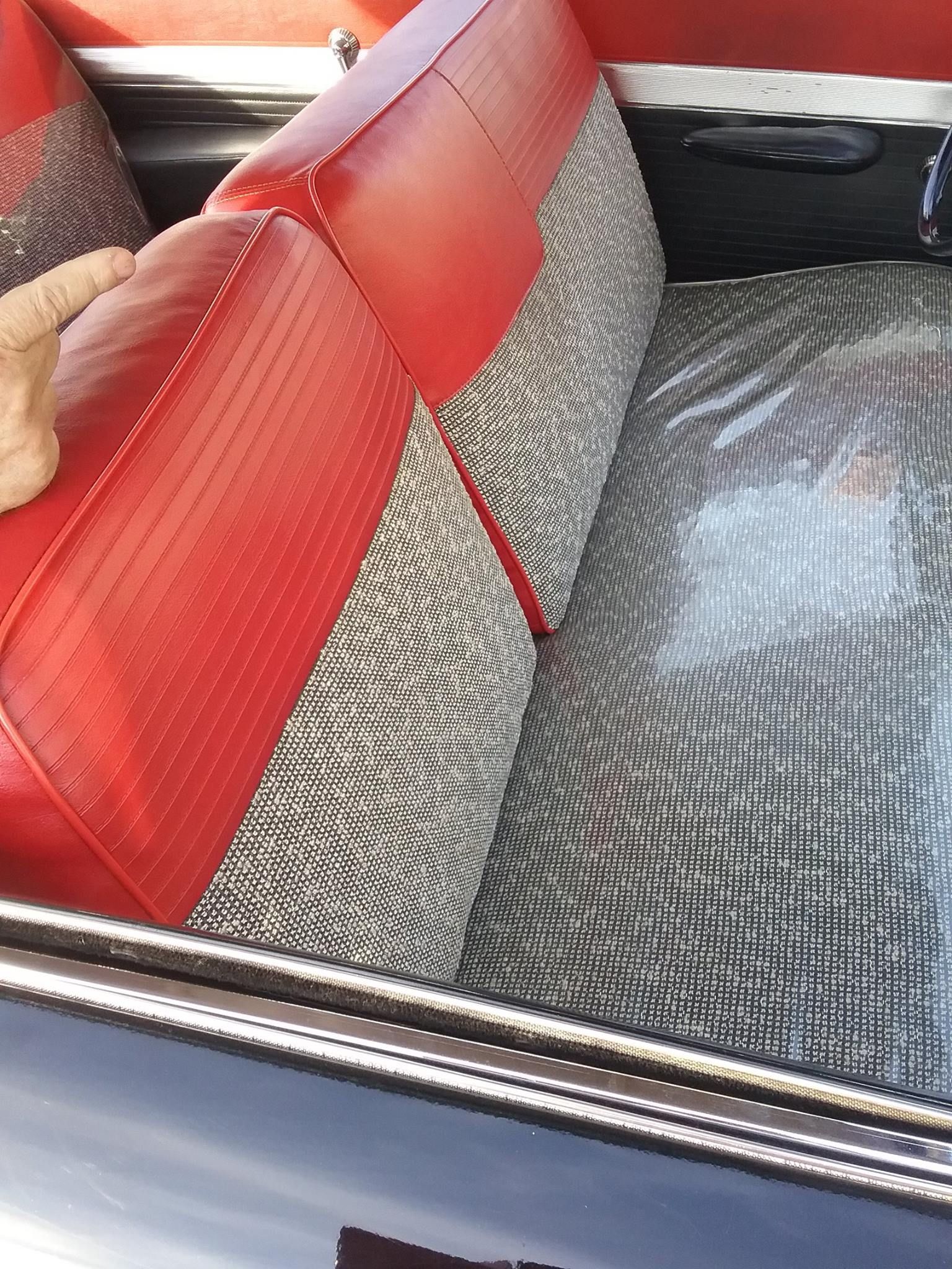 Interior view of a vintage car featuring red vinyl and patterned black-and-white fabric bench seats.