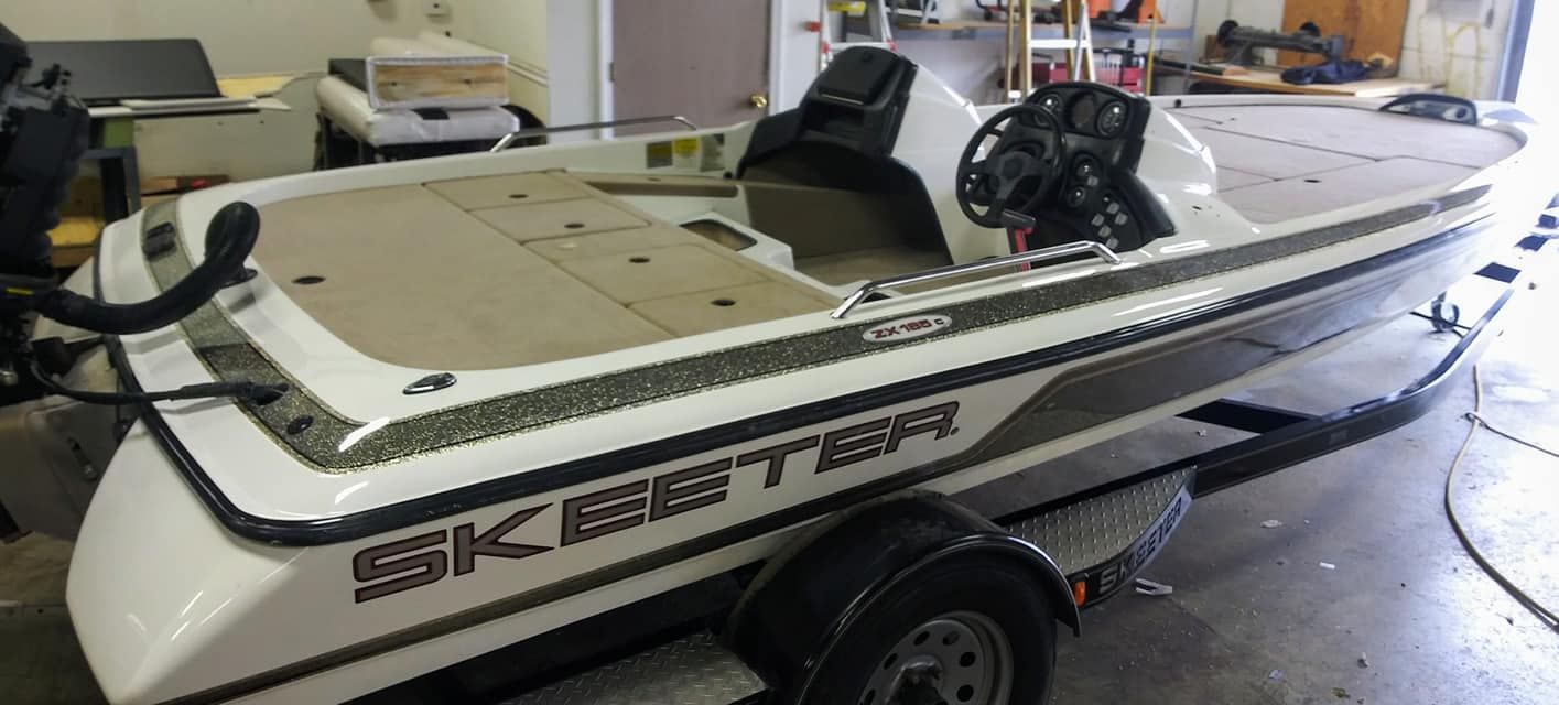 A white and grey Skeeter bass boat sits on a trailer inside a garage.