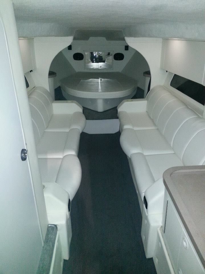 The inside of a boat with white couches and a round table