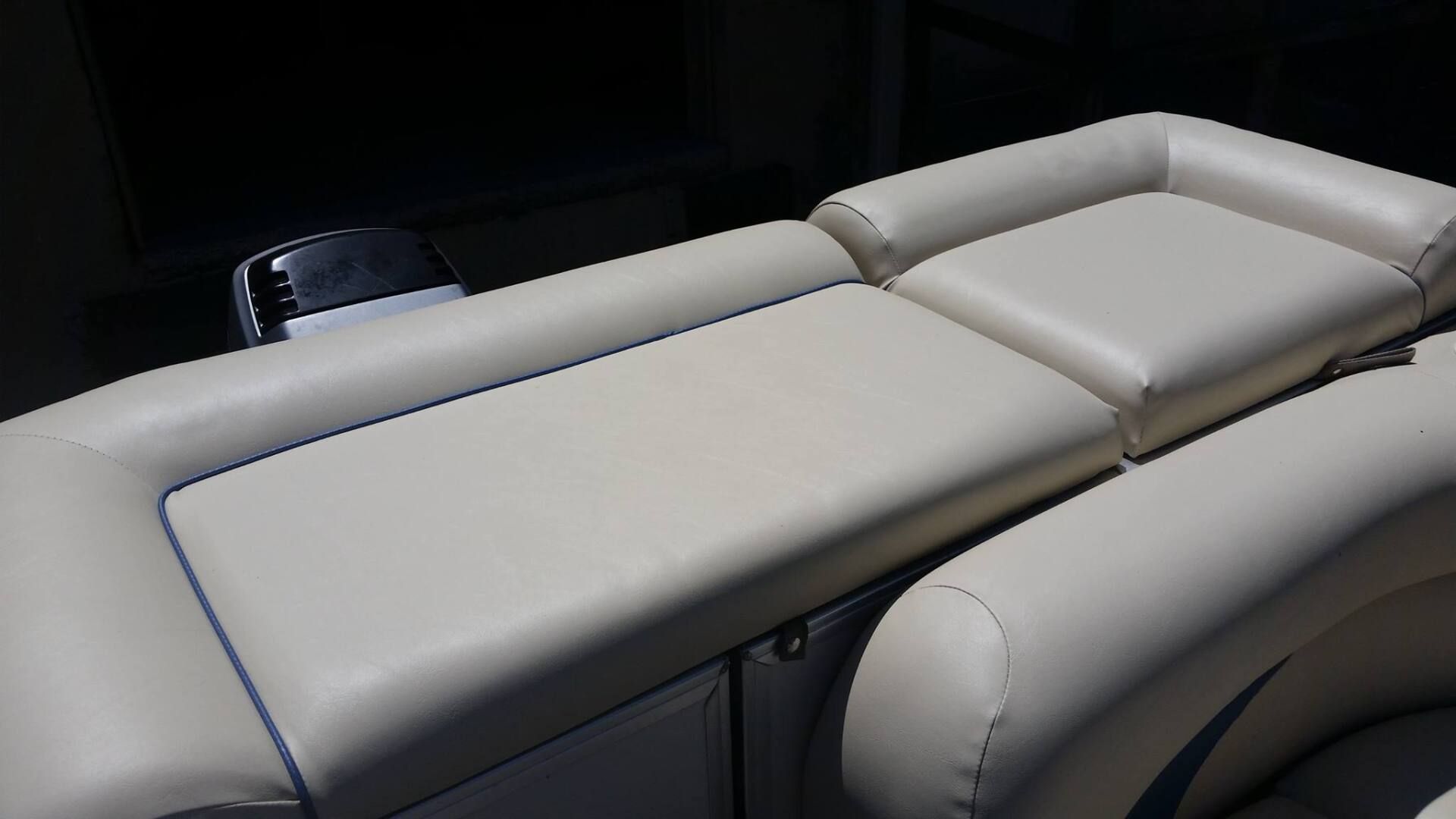 Close-up of beige, padded marine upholstery with blue piping on a boat bench seat.