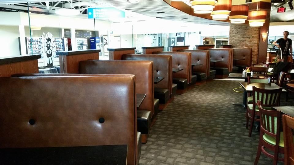 An indoor restaurant dining area featuring rows of brown leather booths and tables with chairs.