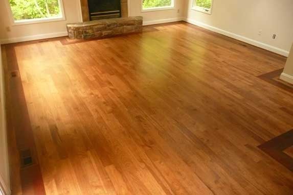 Hardwood floor in a room with windows and a fireplace.