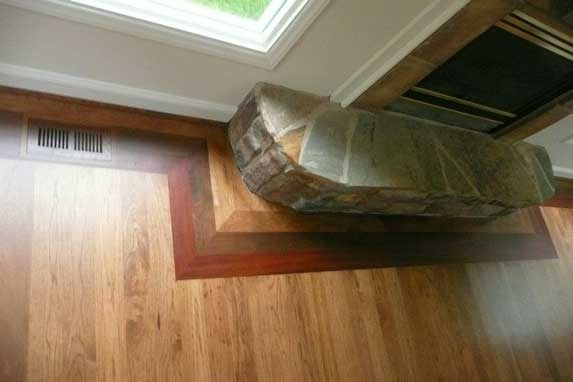 Wooden floors with a fireplace hearth, vent, and window.