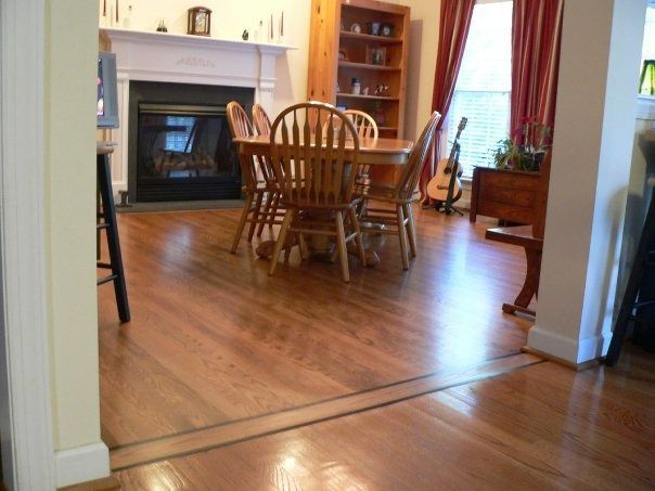 Hardwood floors lead to a dining room with table, chairs, fireplace, and a bookshelf.