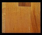 Close-up of a light-brown wooden surface with visible grain and a darker square detail.