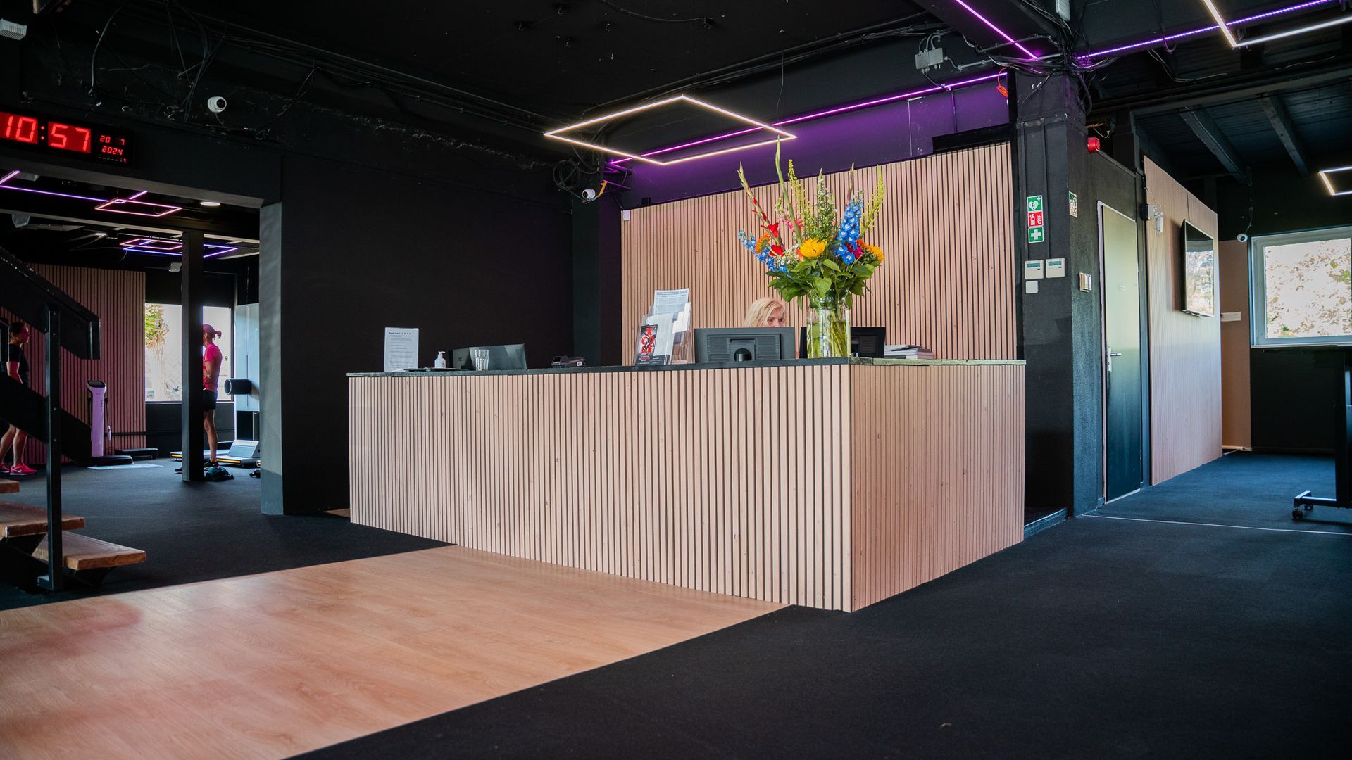 Receptie in een club met een bloemstuk, roze verlichting en een donker interieur.