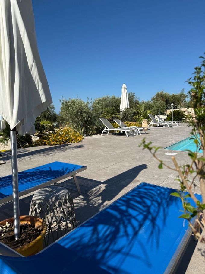 Una piscina con lettini e ombrelloni blu