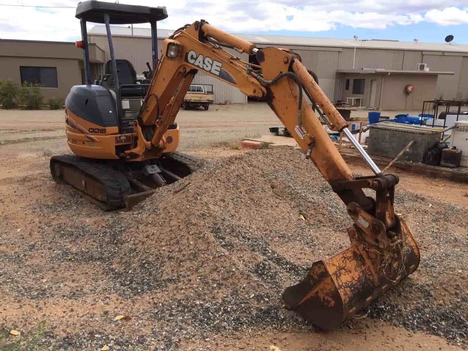 A Man Is Sitting on The Back of A Large Excavator — ASPLUM & CIVIL In Alice Springs, NT