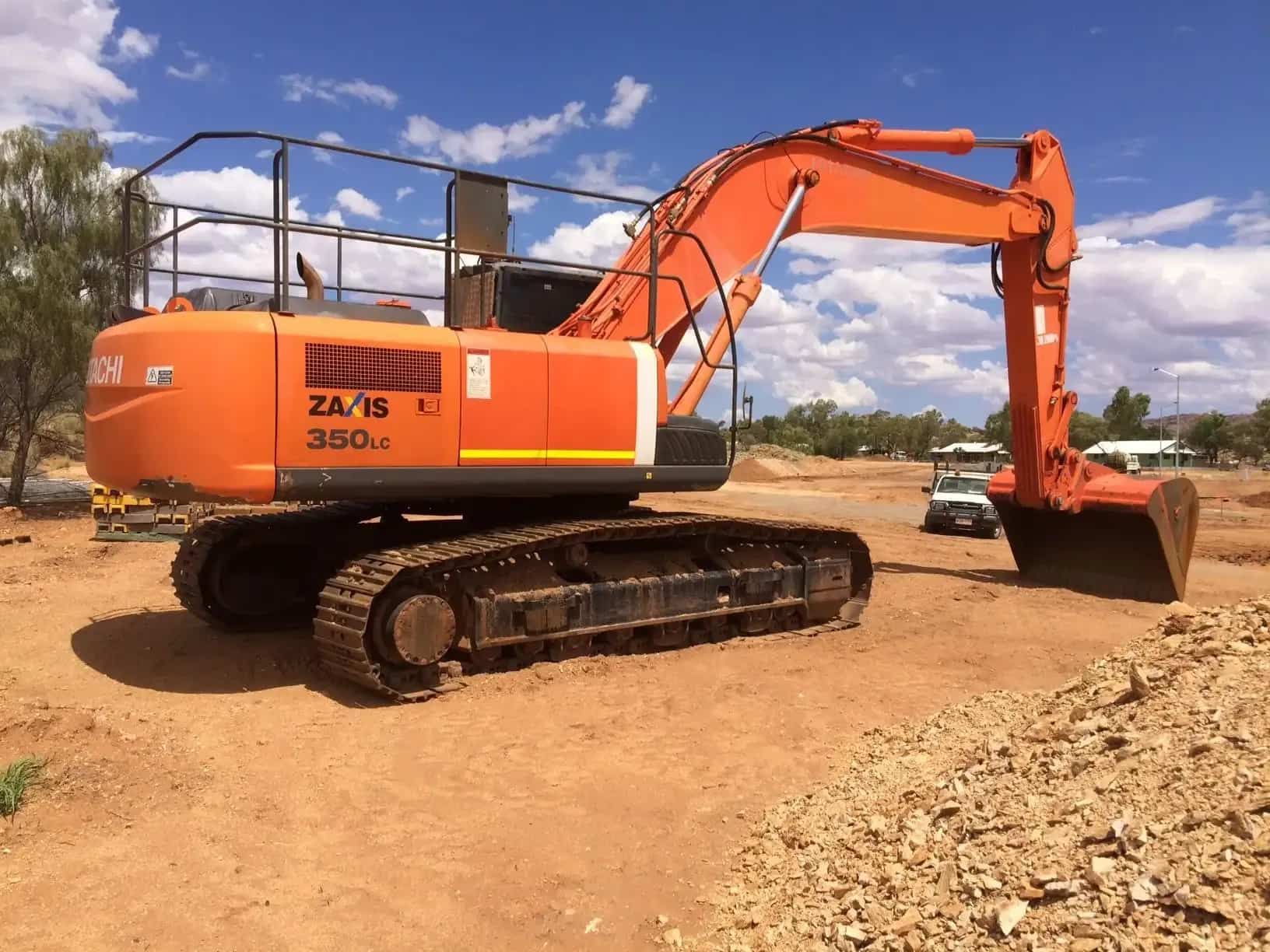 A Large Orange Excavator is Parked in a Dirt Field — Asplum & Civil In Alice Springs, NT