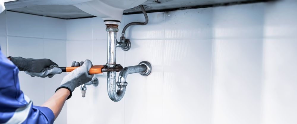A plumber is fixing a sink pipe in a bathroom. — ASPLUM & CIVIL In Alice Springs, NT