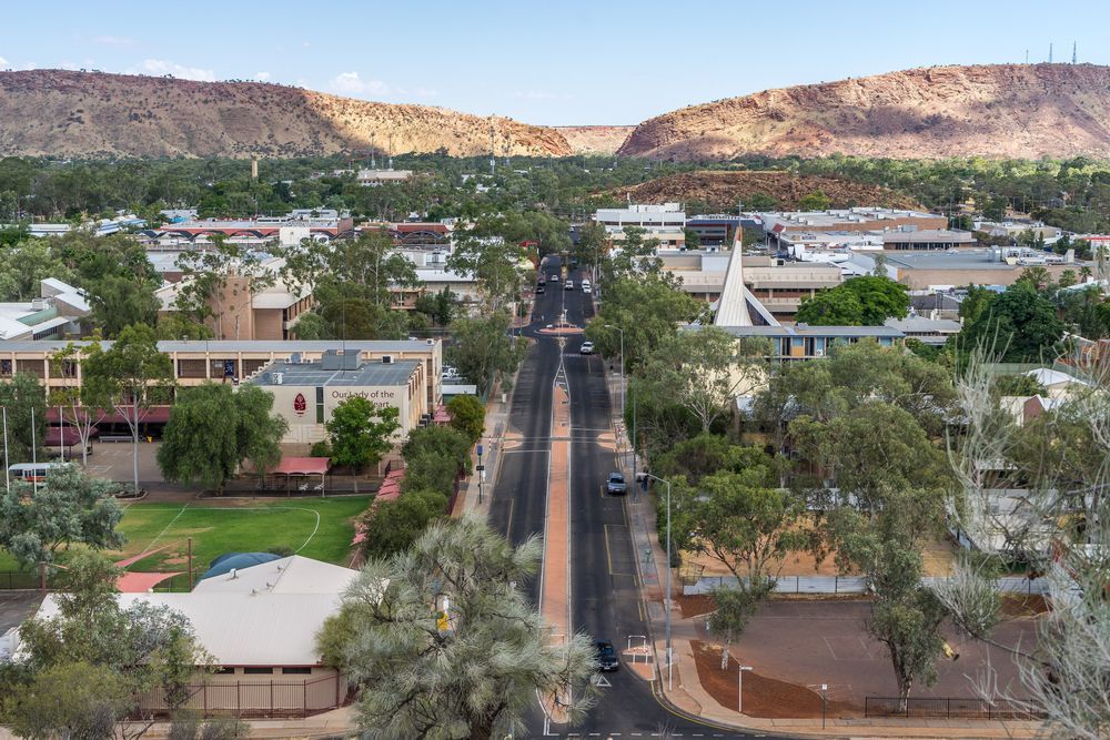 Aerial View of a Town, a Road With Cars, Buildings and Mountains In The Back — ASPLUM & CIVIL In Alice Springs, NT