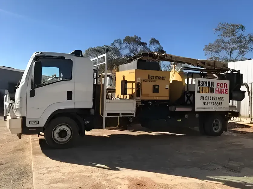 A White Truck With a Yellow Machine on the Back is Parked in a Parking Lot — ASPLUM & CIVIL In Alice Springs, NT