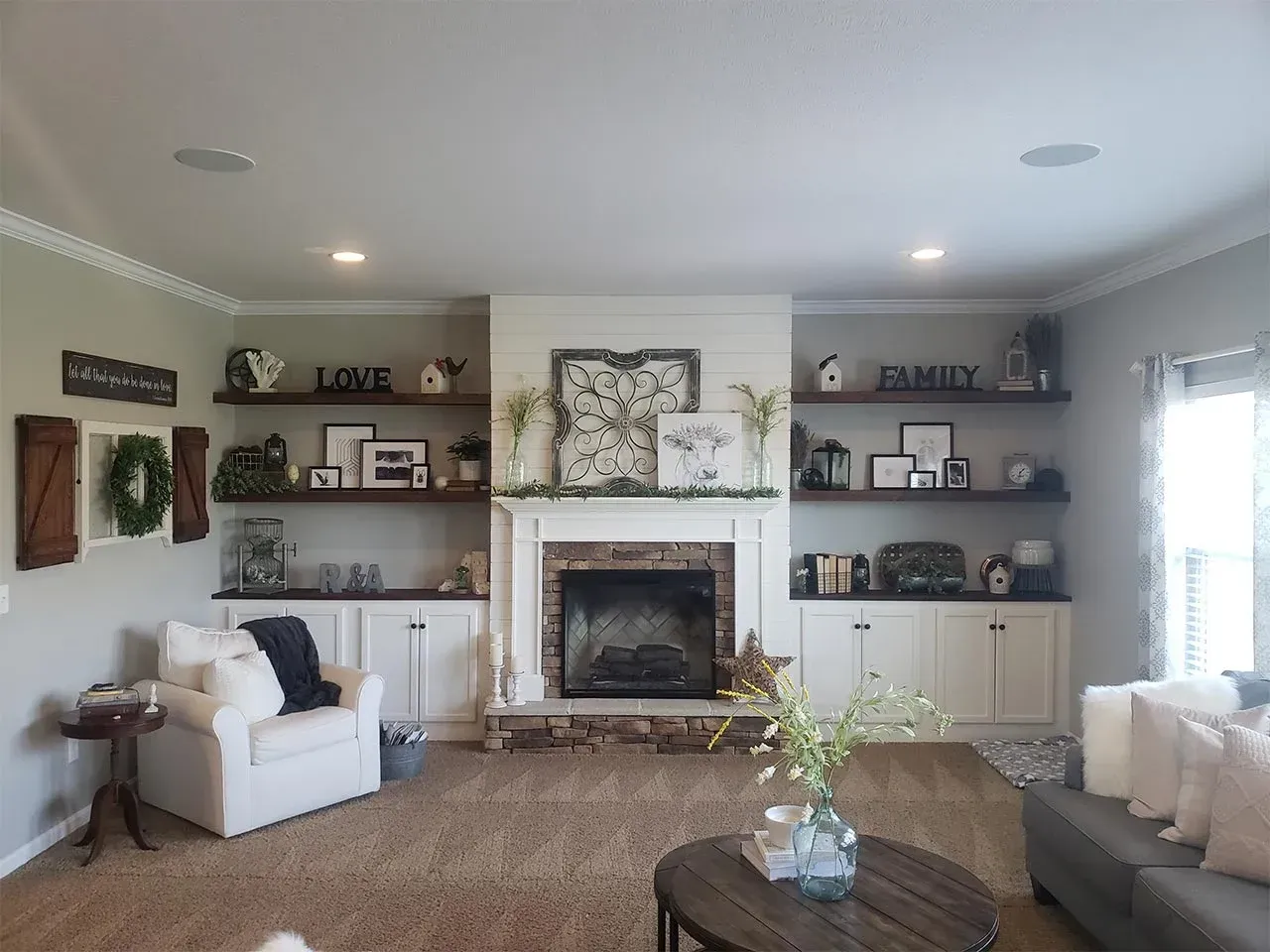Living room with a fireplace, built-in shelves, white cabinetry, and a cozy armchair.