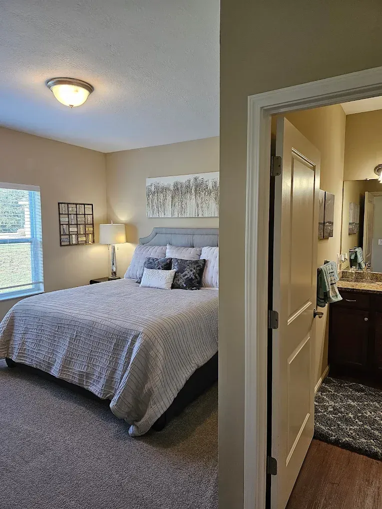 Bedroom with a bed, artwork, and an open door leading to a bathroom.