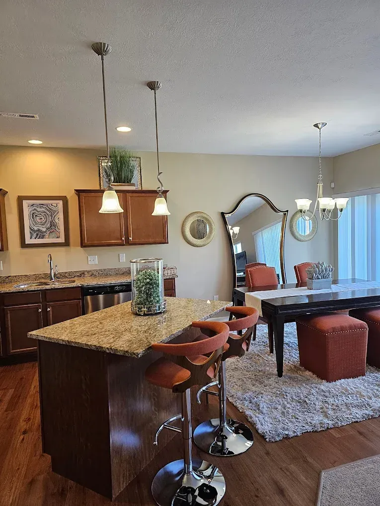 Kitchen with island, bar stools, cabinets, and a dining area with a mirror and table.