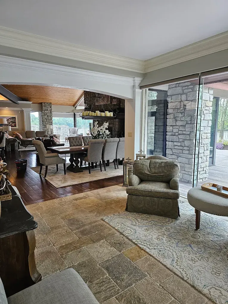 Cozy living room with dining area visible; stone accent wall, large sliding doors. Beige, brown and grey hues.