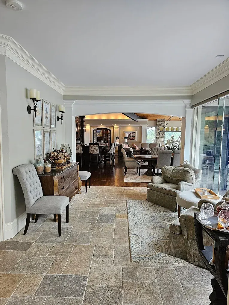 Stone-tiled entryway leading to a living room with seating, a dining area, and outdoor patio view.