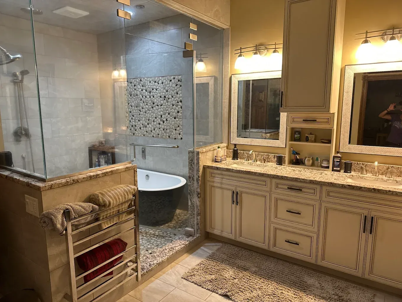 Luxurious bathroom with glass shower, soaking tub, dual sinks, and light wood cabinetry.
