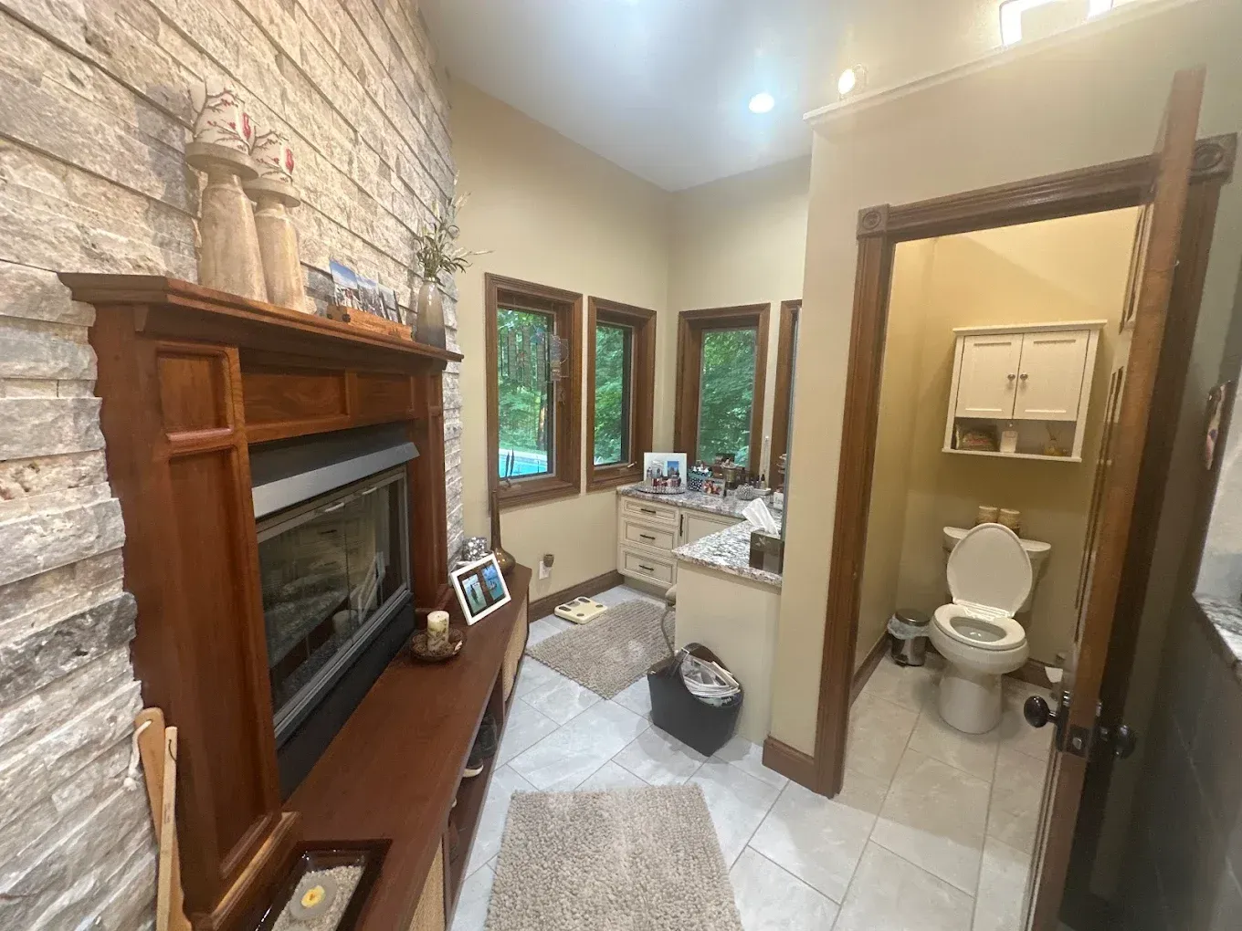 Bathroom with a stone accent wall, fireplace, toilet, and vanity area.