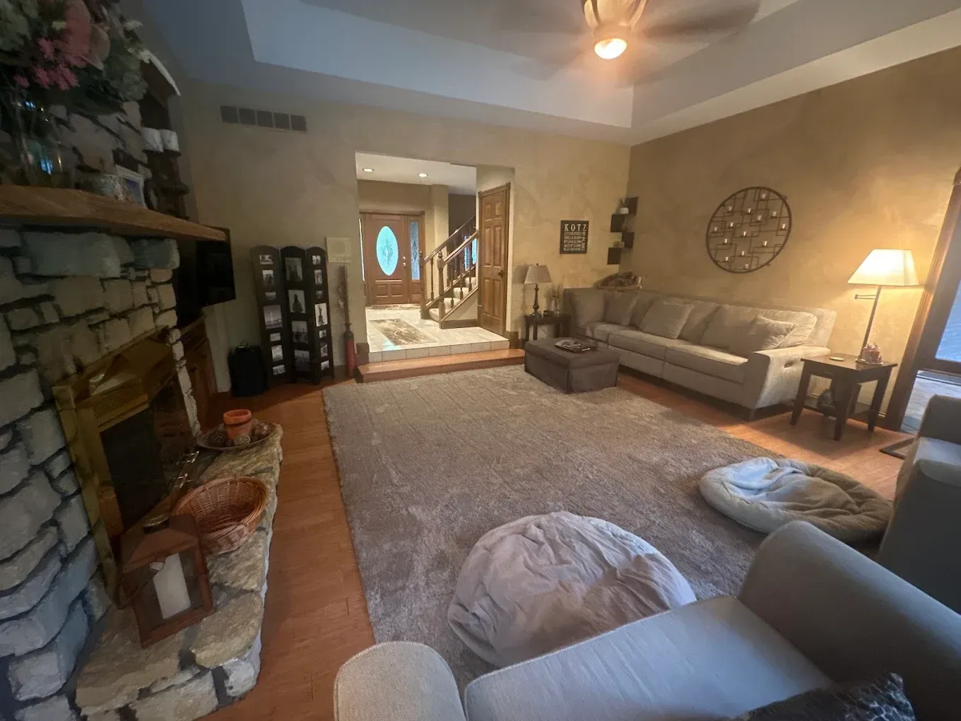 Cozy living room with fireplace, sofa, and entryway, warm tones.