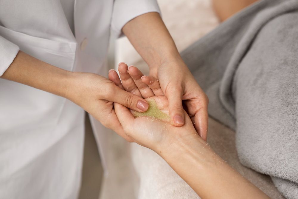 Mãos realizando uma massagem relaxante com creme nas palmas das mãos em um ambiente de spa.