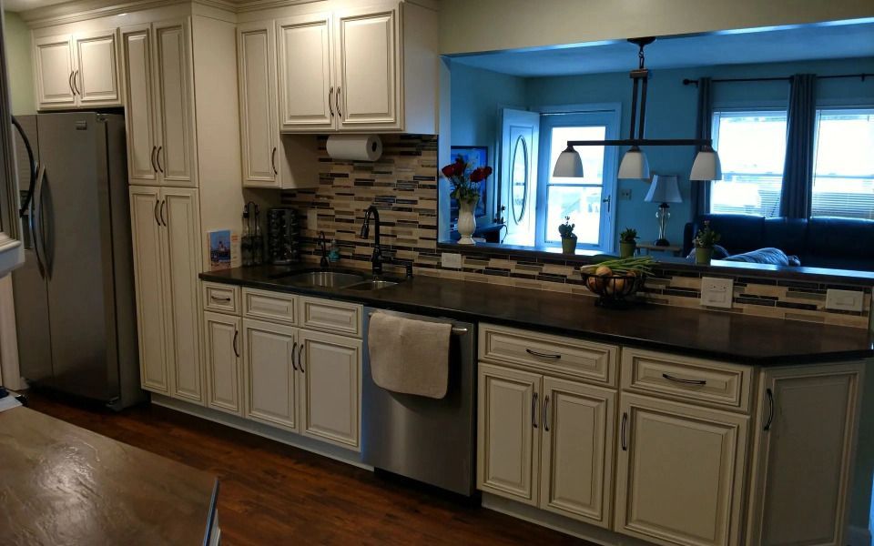 Kitchen with white cabinets, stainless fridge and dishwasher, granite counters, and a window over the sink.