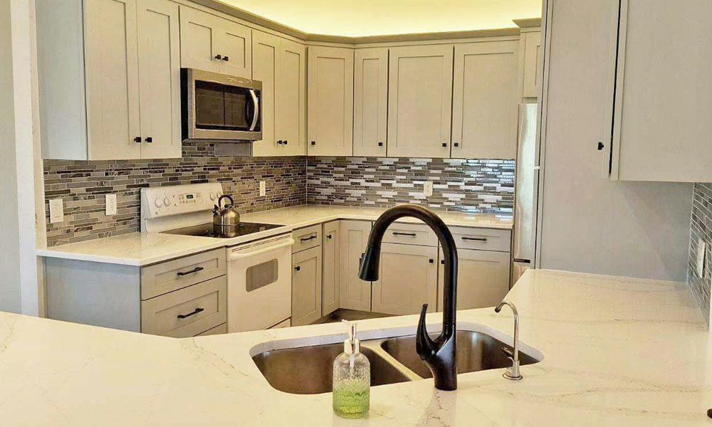 Bright white kitchen with island sink, black faucet, and stainless steel appliances