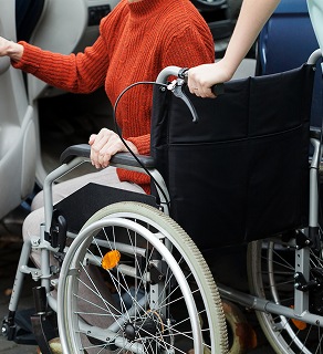 Two people in a wheelchair, one pushing the other, with a red sweater visible