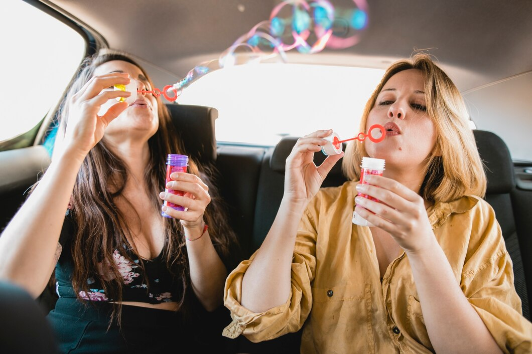 Two people in a car blowing soap bubbles with colorful bubble wands