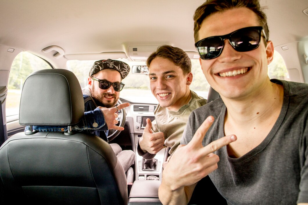 Three smiling friends in a car, one holding up a peace sign; front passenger wears sunglasses.
