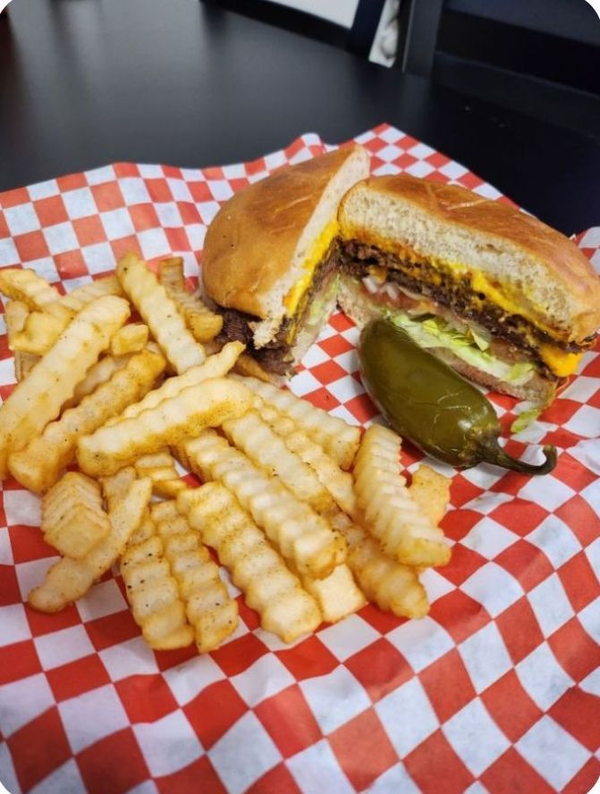 A sandwich and french fries in a basket on checkered paper.