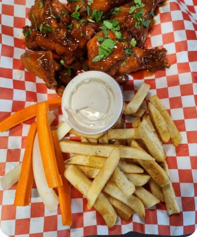 A plate of chicken wings on a cutting board on a wooden table.