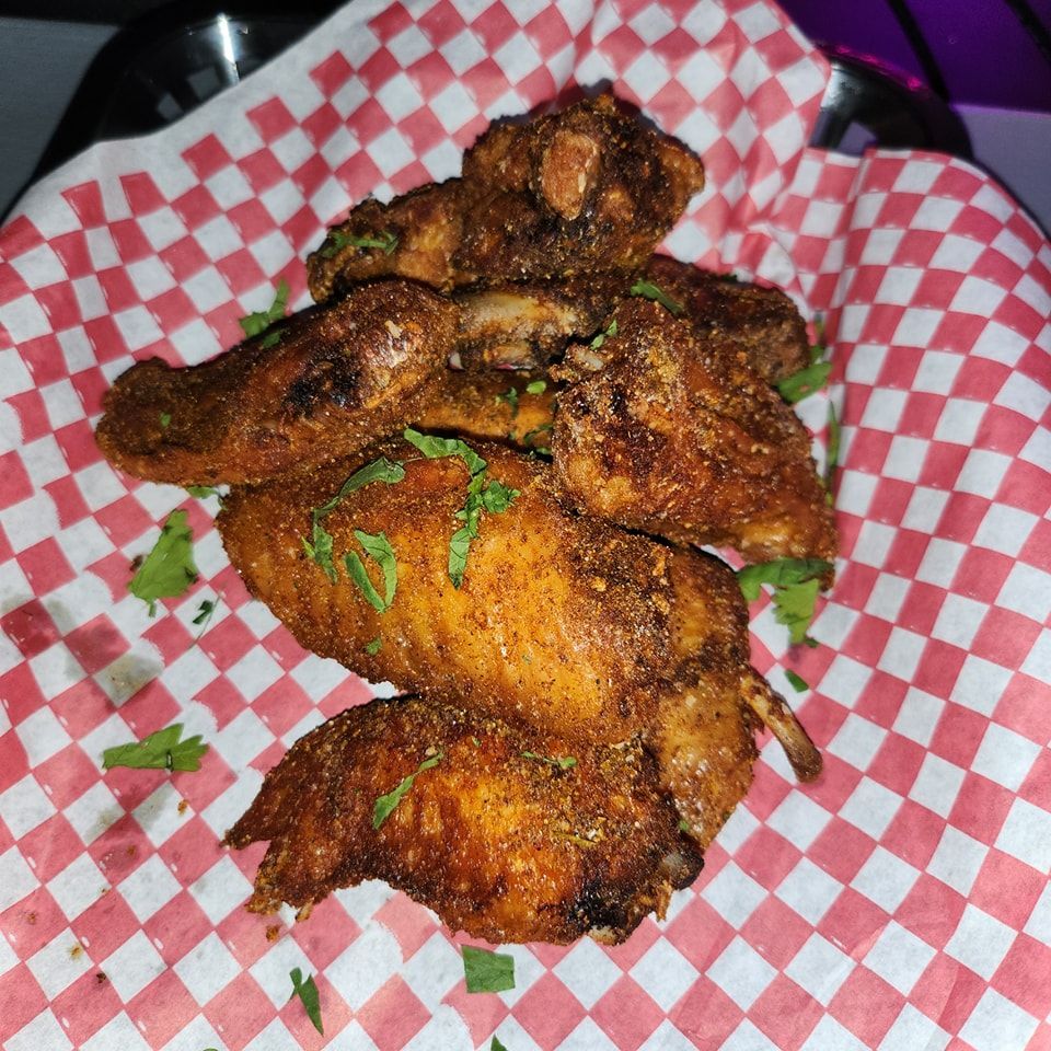 A close up of chicken wings on a red and white checkered paper.