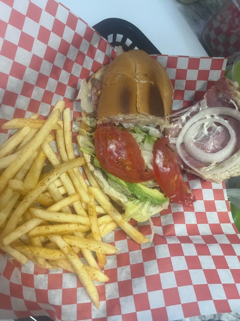 A sandwich and french fries in a basket on checkered paper.