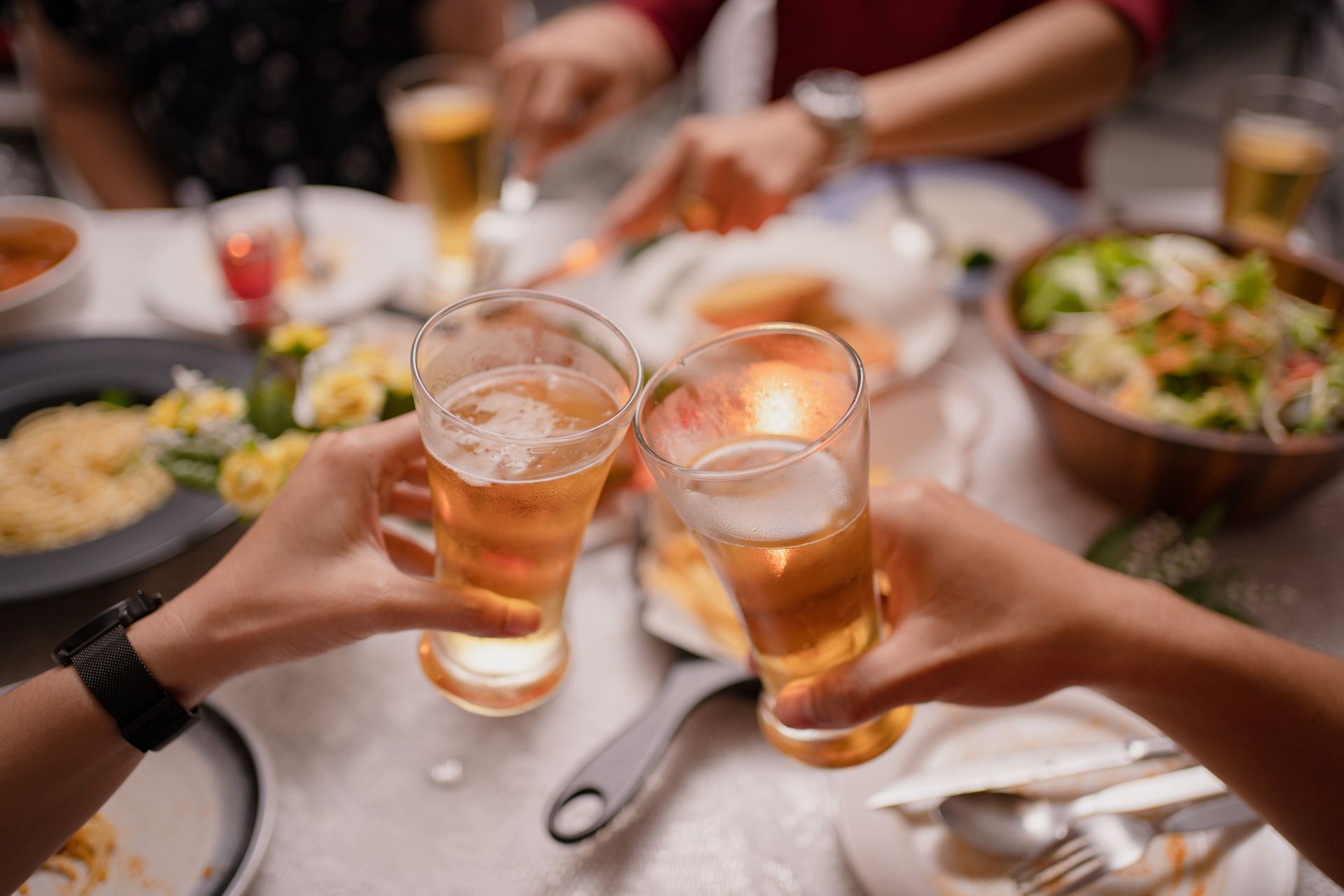 A group of people are toasting with beer at a table.