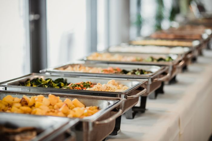 A buffet line with a variety of food on a table.