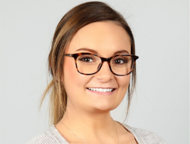 A woman wearing glasses is smiling for the camera.