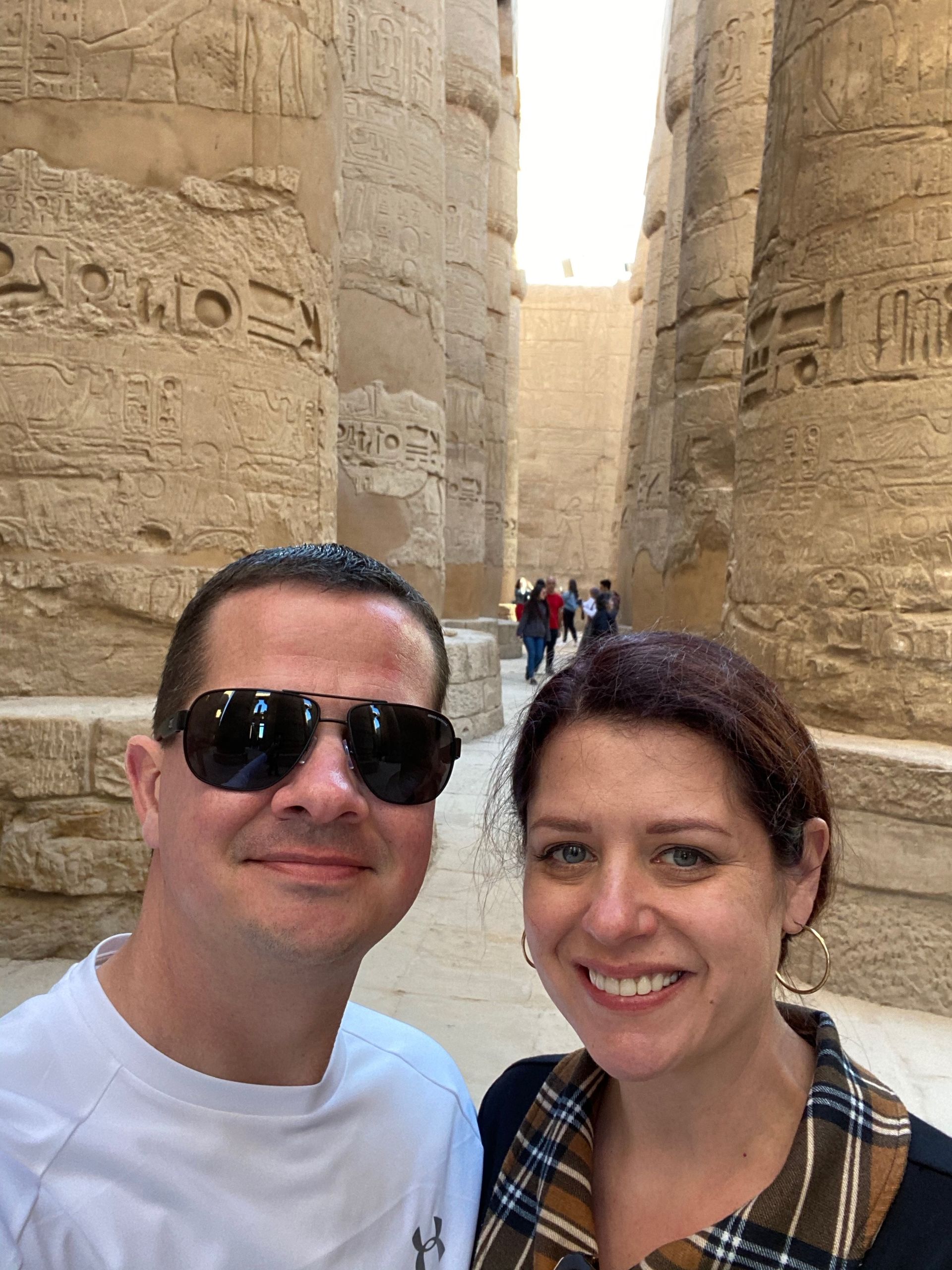 women and man standing side by side A man and a woman are posing for a picture in front of a stone wall.